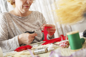 Senior women woman cuts fabric with scissors