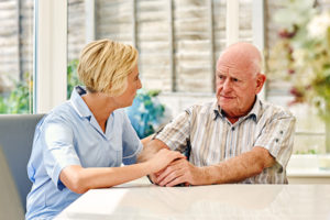 Depressed senior man sitting with female carer