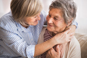 Two senior women at home, hugging