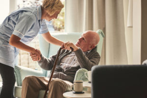 Caregiver helping senior man out of his chair