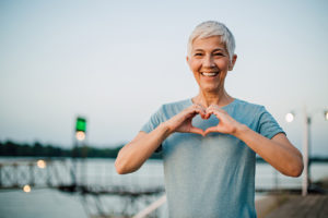  happy senior woman making a heart shape with her hands