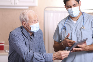 masked senior man talking with health professional