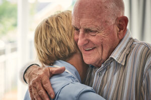 family caregiver hugging senior man