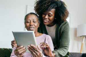 Family caregiver helping senior woman with technology