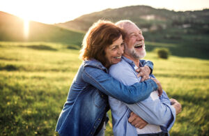 Family caregiver hugging happy senior man