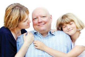 wife and daughter hugging husband with cancer