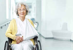 senior lady sitting in wheelchair with arm in sling