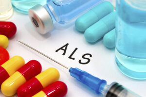 Vials of liquid and loose pills surround a syringe, along with the letters ALS. 