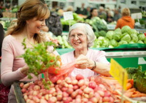 A caregiver helps an older adult choose foods from the grocery store to avoid a decline in senior nutritional health.