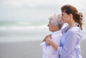  An older adult and her daughter stand together on the beach and contemplate the changes that come with at-home Alzheimer’s care.