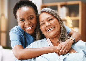 A senior receiving 24-hour care services laughs with her caregiver. 