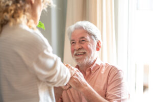 A woman bringing someone home after a stroke holds his hands to help him stand up.