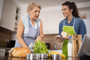 A caregiver helps with managing diabetes in an elderly woman by preparing a healthy meal.