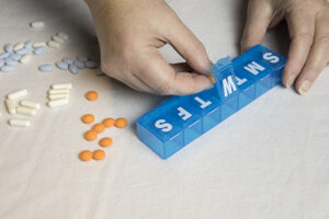 Someone utilizes tips for medication safety at home by placing pills into a pill organizer.