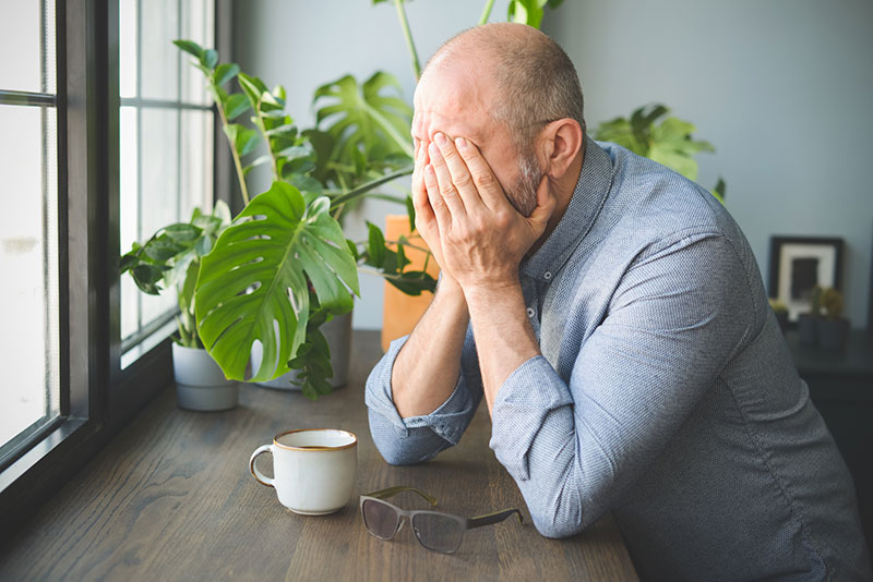 A man experiencing PTSD in later life holds his head in his hands.