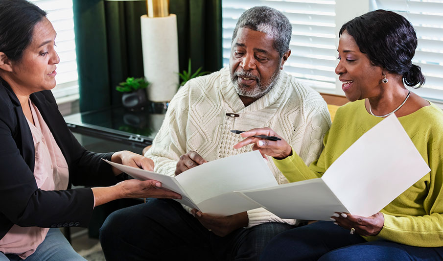 An older man and his wife review their Parkinson’s long-term care plan with their care provider.