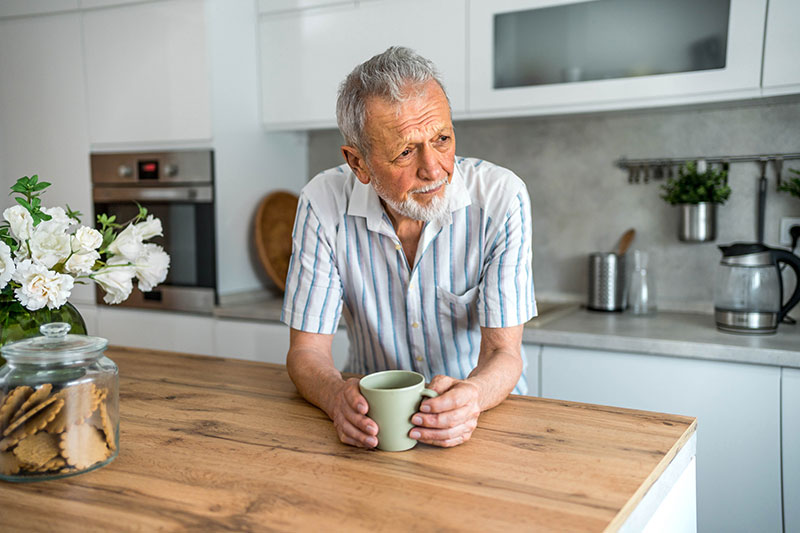 A man leans pensively on his counter, wondering, “Are these mood changes part of Parkinson’s?”