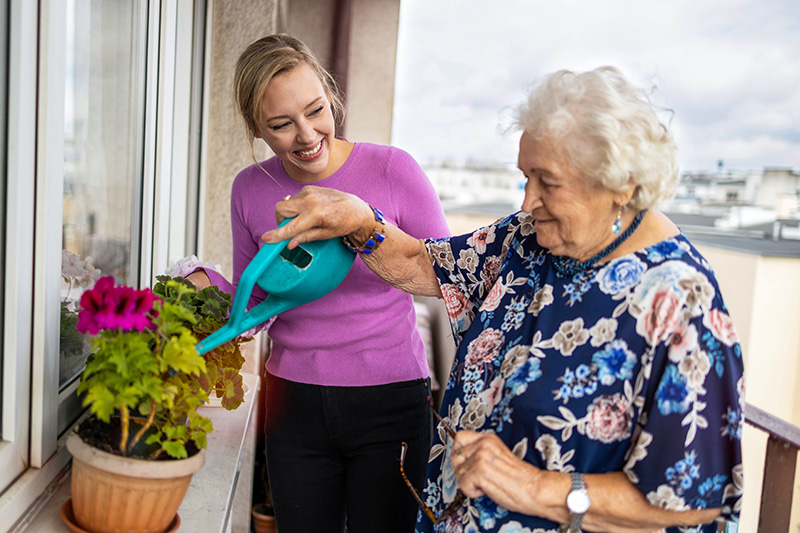 A Creve Coeur home care provider helps an older woman water her plants.